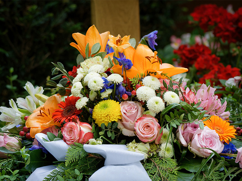 Blumenschmuck mit Rosen und Lilien an Grabst&auml;tte symbolisiert w&uuml;rdevolle Vorsorge f&uuml;r den Trauerfall und liebevolle Erinnerung.