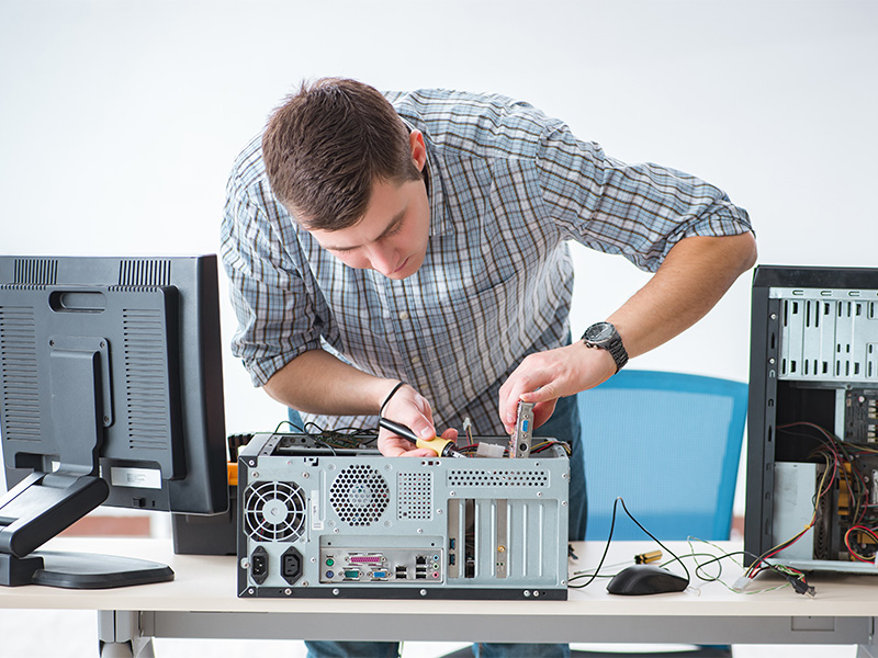 Junger Techniker bietet PC-Service in Bad Homburg an und repariert einen Computer in einer Werkstatt.