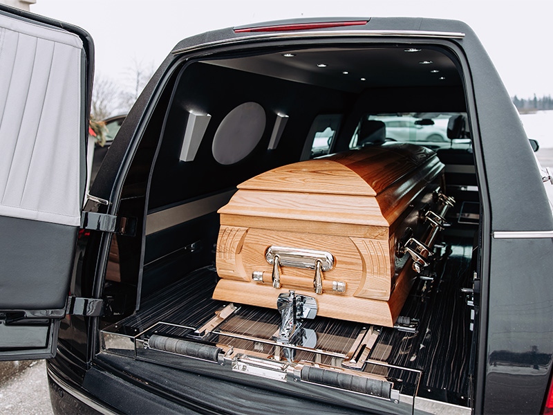Heller Holzsarg im Heck eines schwarzen Leichenwagens als Motiv für einen Bestatter in Usingen