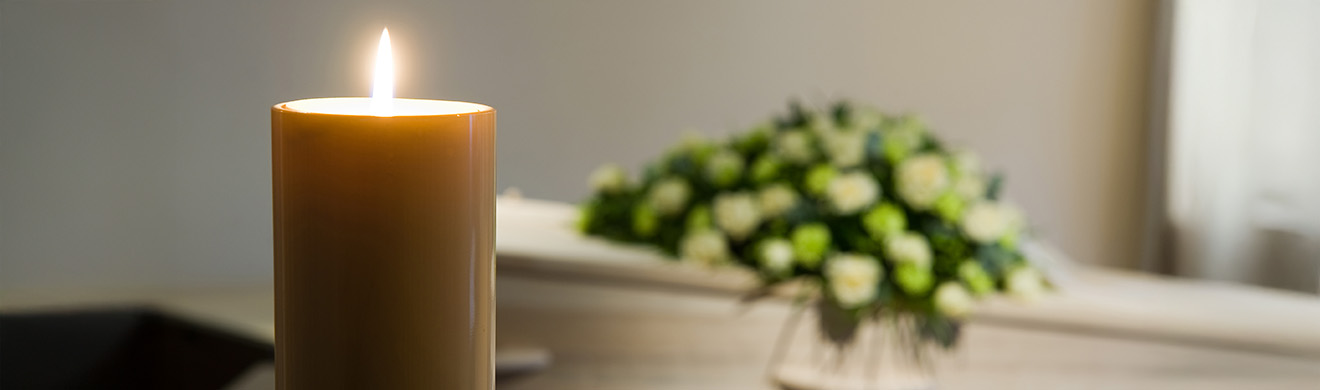 Brennende Kerze vor einem Sarg als Motiv für Informationen zur Erdbestattung in Usingen und zur Beisetzung auf dem Friedhof