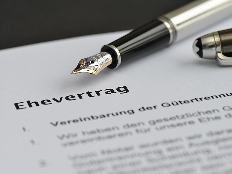 Ein Anwalt für Familienrecht in Königstein erklärt einem Ehepaar ein Dokument – unterzeichnet einen Ehevertrag.