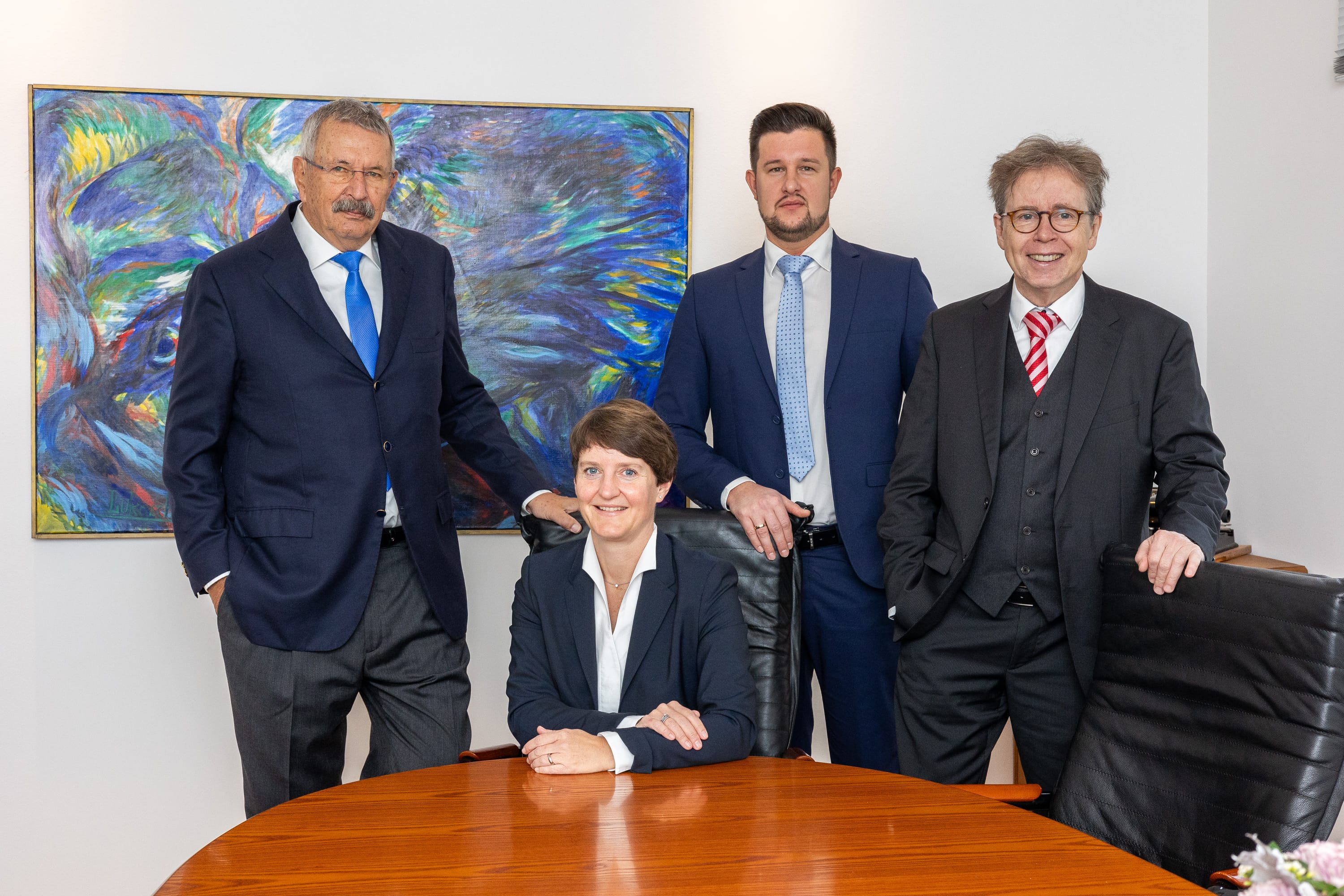 Vier Anwälte der Kanzlei Dr. Aumüller Königstein sitzend und stehend am Besprechungstisch – professionelles Team für Familienrecht und Notardienstleistungen.