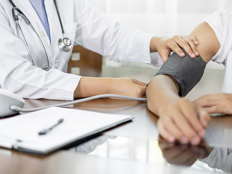Ärztin misst Blutdruck einer Patientin und bespricht Ergebnisse während einer Vorsorgeuntersuchung in moderner Arztpraxis