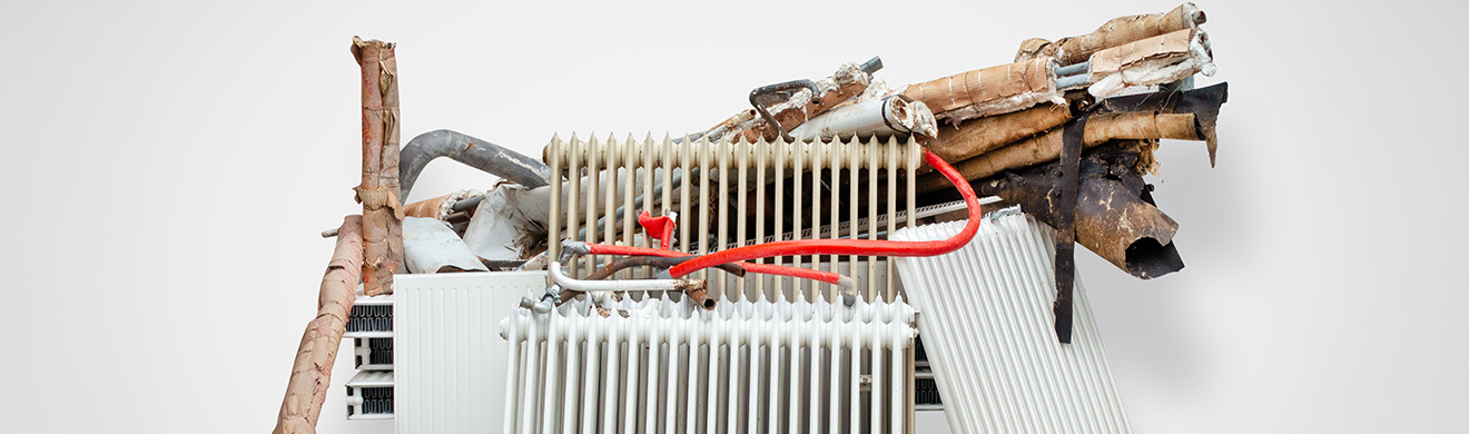 Alte Heizungsanlage in einem Wohnraum vor Austausch, Rohre und Heizkörper sichtbar, Energieeffizienz verbessern in Bad Soden.