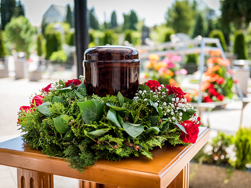 Urne mit weißen Blumen bei einer Trauerfeier als persönlicher Ort des Abschieds und Gedenkens an einen verstorbenen Menschen.