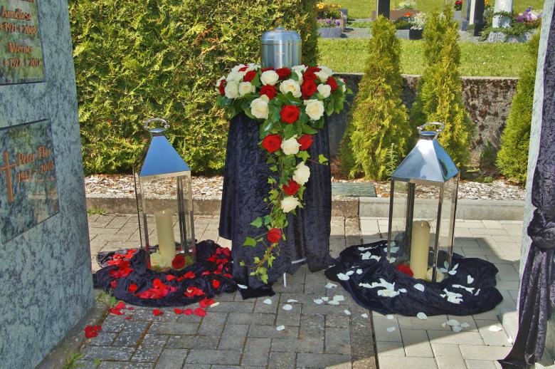 Dekoration einer Urnenbestattung neben einer Trauerhalle mit Kerzen, Blumenbouquet und Urne für einen persönlichen Abschied.